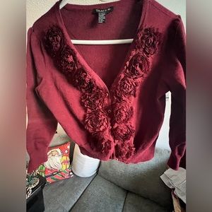Burgundy top or short cardigan. Never worn. Has flowers on trim in the front